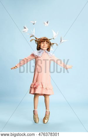Full-length Portrait Of Playful Little Girl, Child In Pink Dress Posing Against Blue Studio Backgrou