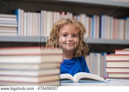 Kid Reads Books In The Library. Schoolboy With Book In School Library. Literature For Reading. Child