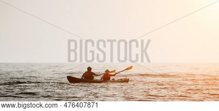 Happy Couple Kayaks In An Inflatable Kayak On The Sea At Sunset. Couple Kanoeing In The Sea Near The