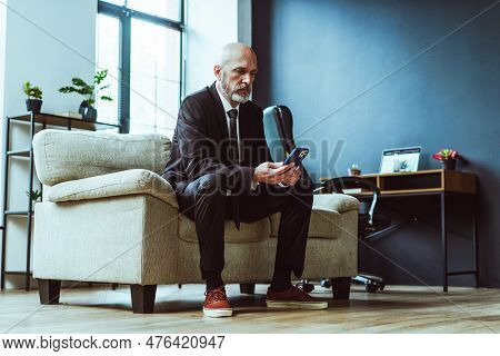 Old Businessman Dressed In Black Suit Can Be Seen Either Texting On Phone Or Browsing Internet. Matu