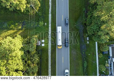 Top View Of Classical American Yellow School Bus Driving On Rural Town Street For Picking Up Kids Fo