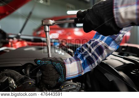 Female Auto Mechanic Unscrewing A Nut To Replace A Car Spark Plug.
