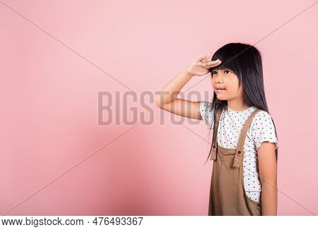 Searching Concept. Asian Little Kid 10 Years Old Looking Far Away With Hand Over Head At Studio Shot