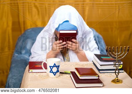 A Jewish Woman In A Kisui Rosh Headdress And A Prayer Veil Kisses The Siddur. Horizontal Photo