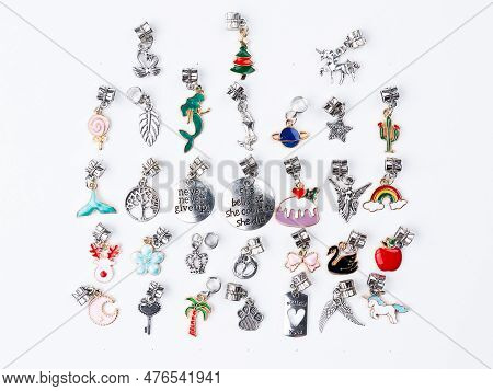 A Variety Of Metal Charms For A Child's Necklace Or Bracelet. Many Charms Isolated On A White Backgr