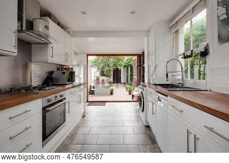 Cambridge, Cambridgeshire, England - June 8 2018: Luxury Fitted Kitchen With Bifold Doors Open To Ur