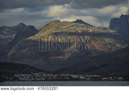 Dramatic Light And Clouds Over Mountain Peaks Of Northern Norway With A Suburb Of Tromso Underneath,