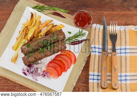 Serving Of The Baked Lula Kebab With French Fries, Chopped Vegetables And Sauce On The White Square 