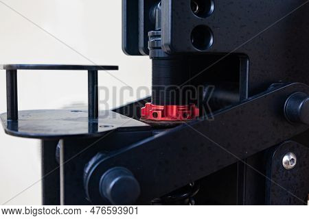 A Steel Mechanism With A Threaded Stem And A Red Clamping Nut On It.