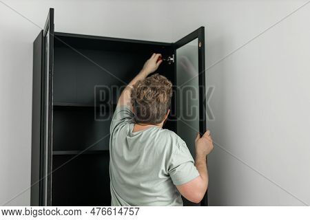 Young Attractive Man Assembles Furniture - Handwerker And Interior Objects Concept
