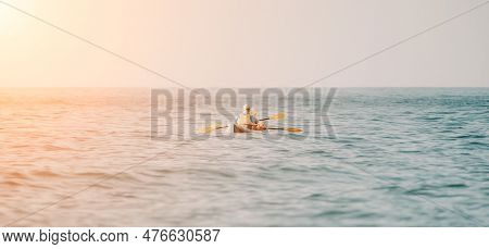 Happy Couple Kayaks In An Inflatable Kayak On The Sea At Sunset. Couple Kanoeing In The Sea Near The