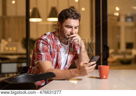 Portrait Of A Cheerful Man With Smart Phone At Home. Guy Using Phone At Home. Middle Eastern Mature 