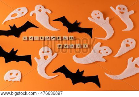 White Ghosts And Bat Craft For Halloween Party. Wrapping Paper Ghost On Orange Background Top View. 