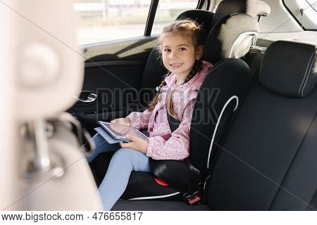 Adorable Child Girl Playing Game With Digital Tablet While Sitting In Car Seat Of Car During Trip. H