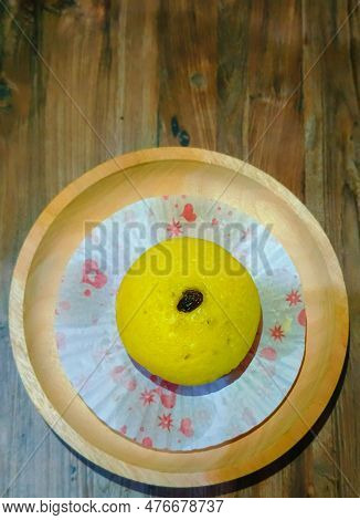 A Mud Cake Topped With Raisins On A Large Wooden Bowl