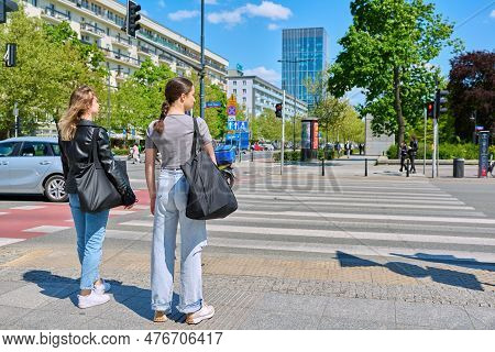 Young Women Cross The Road At Pedestrian Crossing, In Modern European City