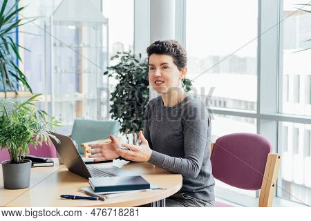 Neutral Gender Middle Aged Woman In Casual Clothing Having Conversation In Office While Working Lapt