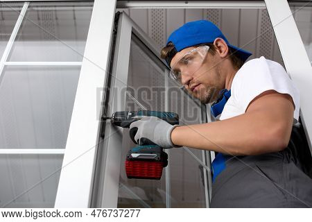 Serious Man In Uniform And A Screwdriver Fixes The Plastic Door To The Base. Professional Installati