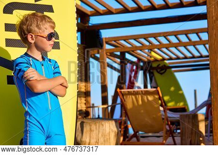 Fashionable Little Guy In A Blue Swimsuit And Sunglasses Poses Carelessly Against The Background Of 
