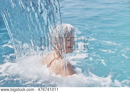 Senior Caucasian Smiling Woman With Gray Hair Enjoying Falling On Her Shoulders Flow Of Water. Hydro