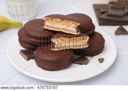 Tasty Banana Choco Pies And Pieces Of Chocolate On White Table, Closeup