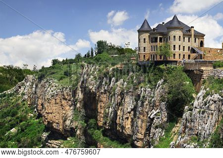 A Castle With A Black Rooftop On A Hilltop Above Fantastic Rocks.