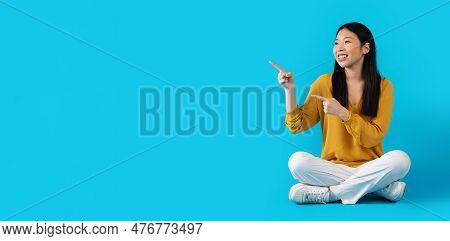 Happy Young Asiam Lady Pointing At Copy Space On Blue