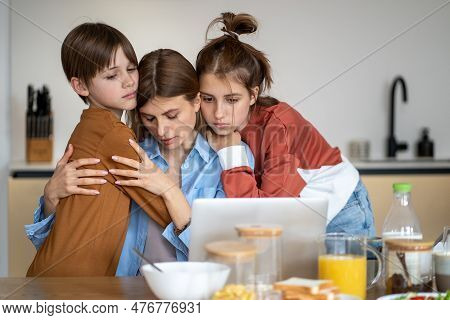 Portrait Of Sad Mother Hugging With Kids Son And Daughter While Sitting In Front Of Laptop Computer 