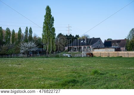 Dendermonde, East Flanders, Belgium - May 1, 2023 - Green Lawn And A Farm At The Flemish Countryside