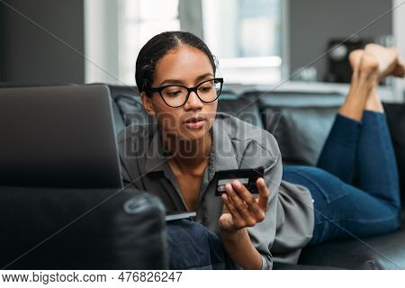 Young Female Entrepreneur In Thought Sitting On The Floor In The Kitchen With A Laptop On Her Legs