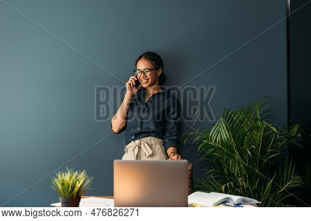 Young Female Entrepreneur In Thought Sitting On The Floor In The Kitchen With A Laptop On Her Legs