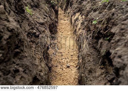 A Trench Dug In The Yard Along The Fence To Lay The Drainage Pipe,visible Yellow Sand.