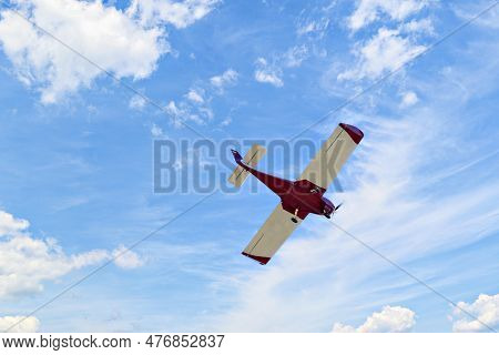 Single Engine Ultralight Plane Flying In The Blue Sky With White Clouds