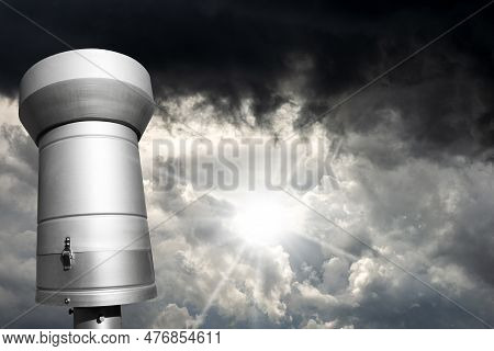 Closeup Of A Weather Station With A Metallic Rain Gauge Or Pluviometer Against A Dramatic Sky With S