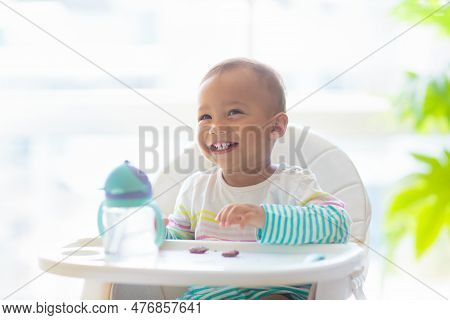 Baby Eating In High Chair. Asian Baby Boy With Drink And Lunch. Infant Weaning And Introducing Solid
