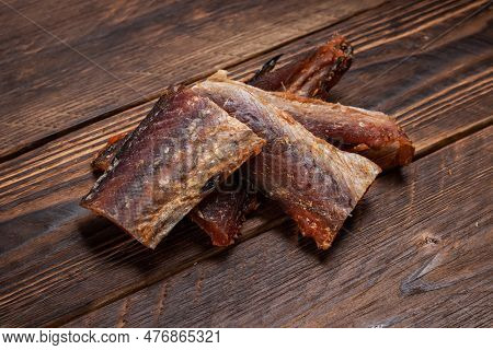 Pieces Of Cleaned Dried Fish On Wooden Background. Dry Peppered Pollack. Amber With Pepper.