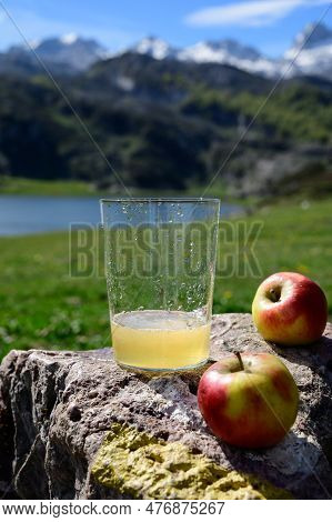 Glass Of Natural Asturian Cider Made From fermented Apples With View On Covadonga Lake And Tops Of P