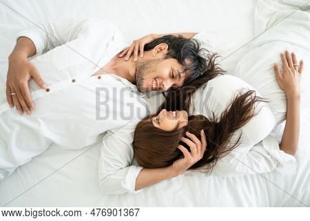 Happy Young Couple Relaxing In Home Bedroom After Waking Up In The Morning.