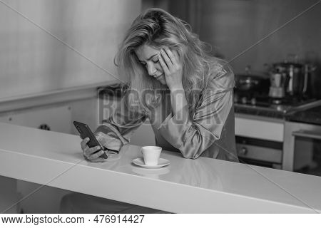 Sad Woman Drink Coffee And Using Phone At Home In Morning. Tired Female Madel Chatting Smartphone In