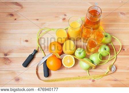 Apple Juice, Orange Juice, Oranges, Apples, Jumping Roap And Measuring Tape Near On Wooden Table. To