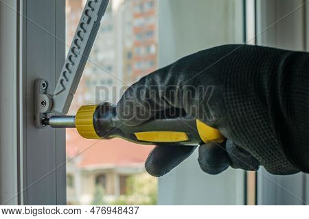 Male Using Screwdriver Tightens Screw That Fixes Plastic Window Opening Limiter Close-up Of Gloved H
