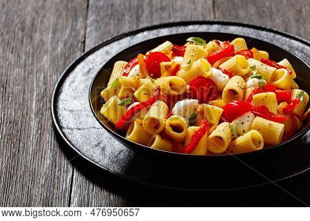 Roasted Pepper Tomato Mozzarella Pasta Salad In Black Bowl On Dark Oak Wood Table, Landscape View