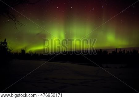 Night Show Of Green Lights Of Aurora Borealis Or Northern Lights In The Forest Valley.