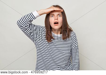 Shocked Surprised Woman With Brown Hair Wearing Striped Shirt Standing Isolated Over Gray Background
