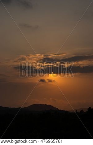 The Sun Sets, Painting The Sky In A Dramatic Orange Hue. Silhouetted Clouds Sit Against This Tranqui