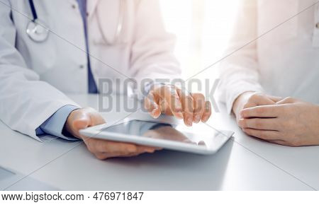 Doctor And Patient Sitting Near Each Other At The Desk In Clinic. The Focus Is On Female Physicians 