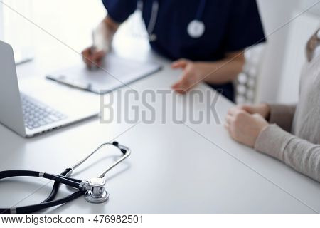 Stethoscope Lying On The Tablet Computer In Front Of A Doctor And Patient At The Background. Medicin