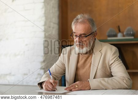 Serious Eldery Businessman Signing Document At Office Table.