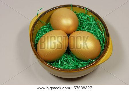 Three Golden Eggs In A Bowl On Green Grass