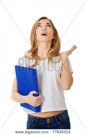 Surprised woman looking up, holding binder.